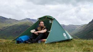 tent in field on top of hill with outdoorsy person sat inside