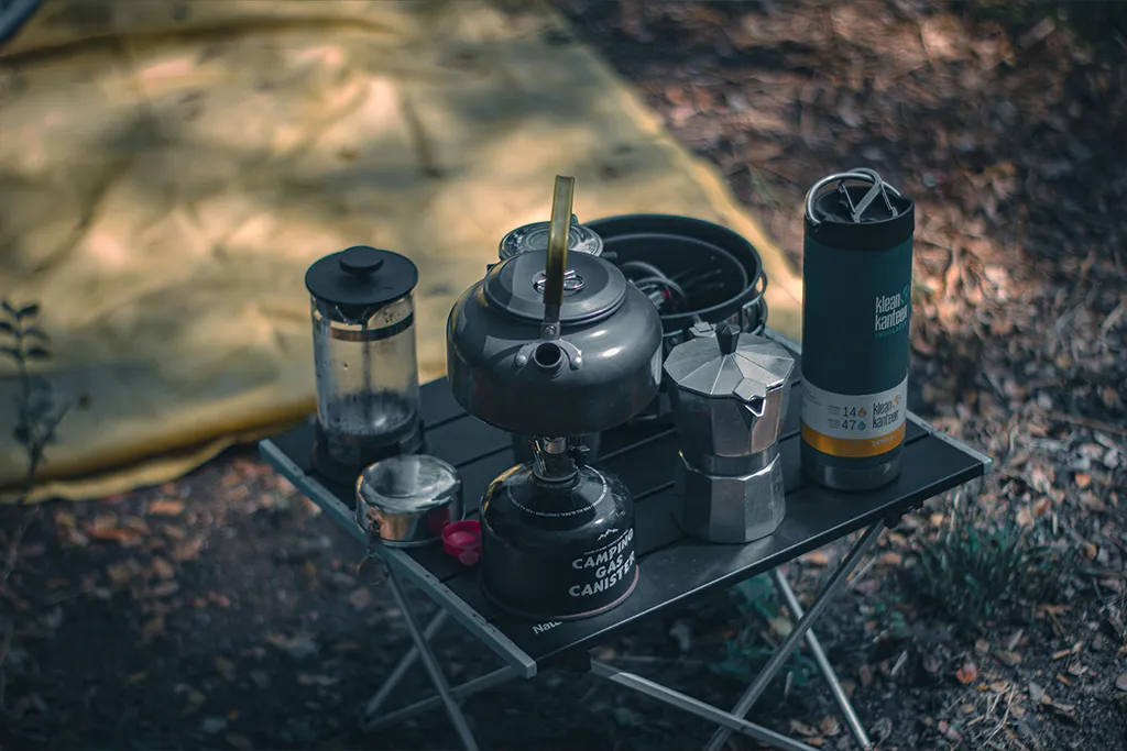 camping table in forest with cooking utensels on