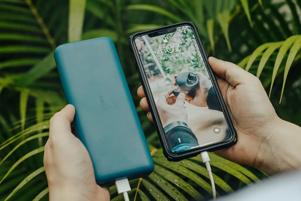 Man charging phone in forest with powerbank