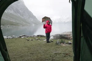 camping in the rain with an umbrella by a lake