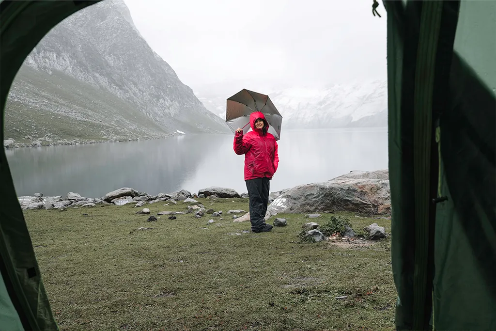camping in the rain with an umbrella by a lake