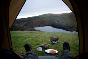 View from inside a tent overlooking a lake and hills during a one-night wild camp in the UK